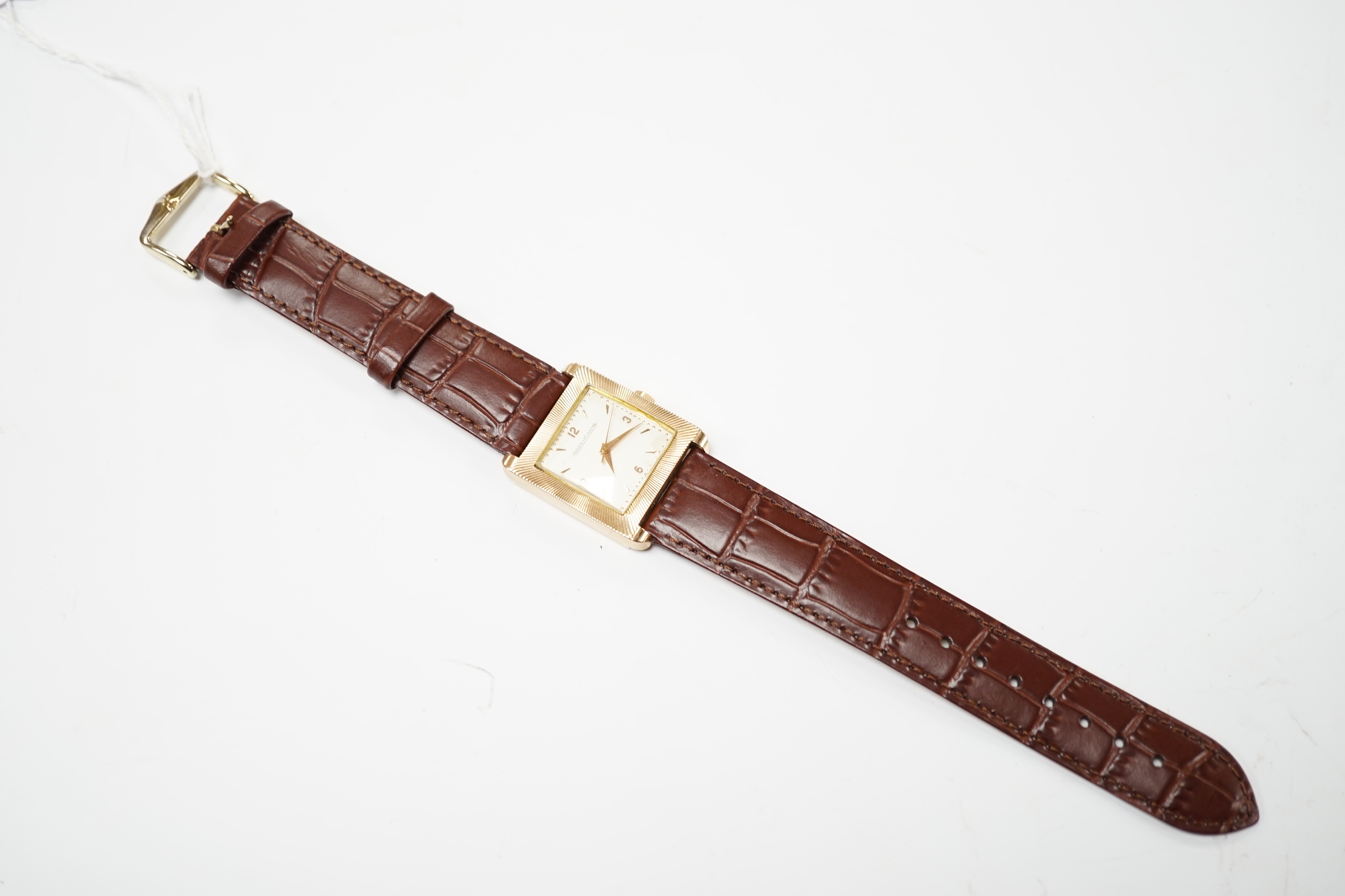 A gentleman's 18ct gold Jaeger LeCoultre manual wind dress wrist watch, with square dial, milled bezel and baton and quarterly Arabic numerals, on associated leather strap, case diameter 26mm, gross weight 31.8 grams.